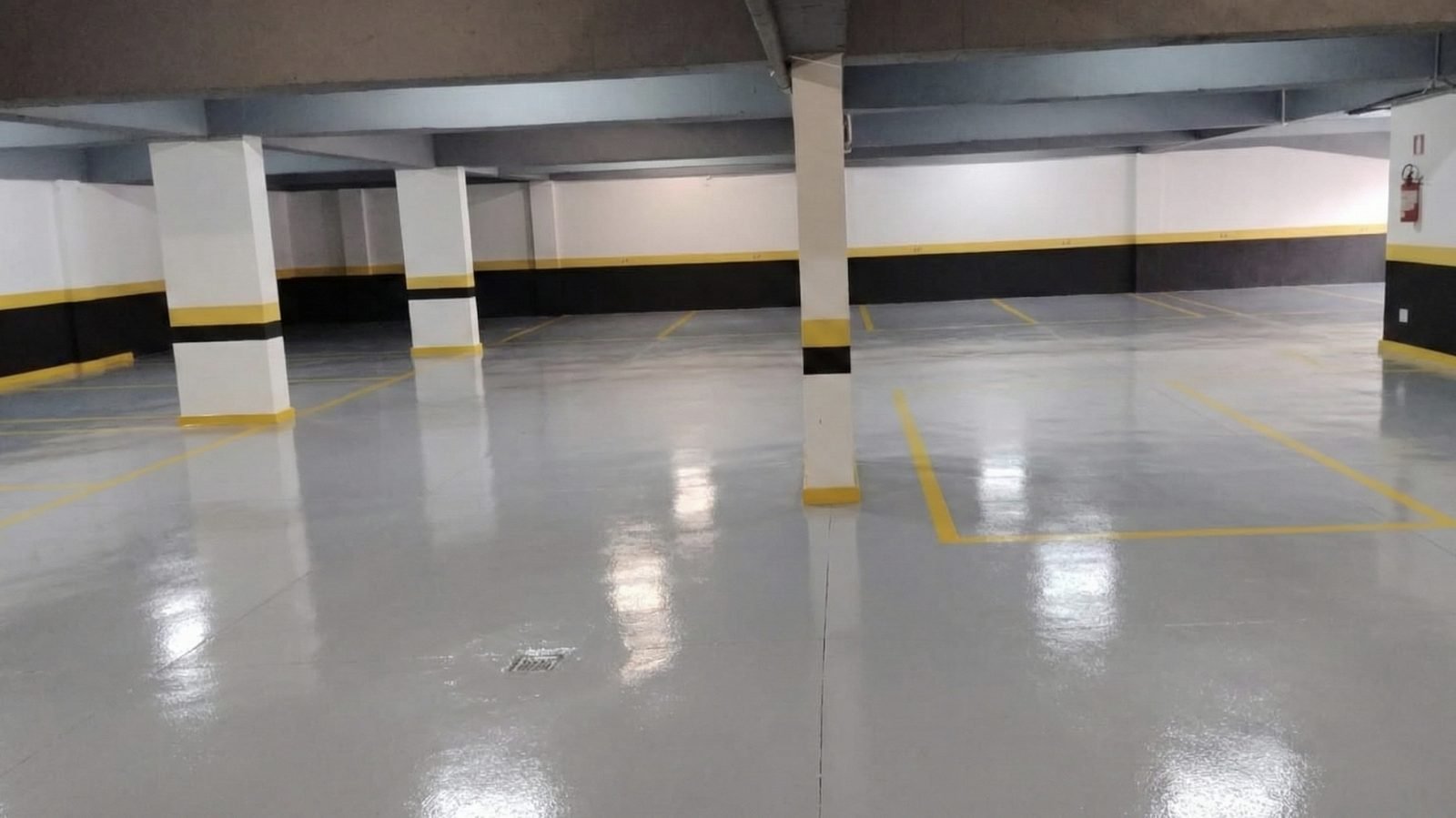 Garagem de condomínio em Belo Horizonte com piso de pintura epóxi cinza e demarcação de vagas